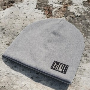 Könnte beinhalten: Eine graue Mütze mit einem schwarzen Patch, auf dem "B01" steht.