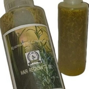 May include: Two clear glass bottles with red caps filled with a yellow liquid and herbs. The larger bottle has a label that reads "Rosemary & Lemongrass Hair Regrowth Oil 4 FL OZ".