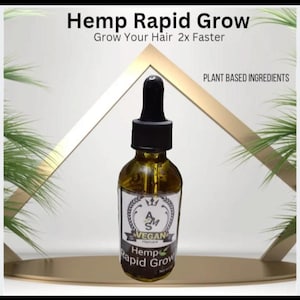 May include: A brown glass bottle with a dropper top and a label that reads "Hemp Rapid Grow" and "Vegan Haircare". The bottle is sitting on a gold surface with green foliage in the background. The label also says "Plant Based Ingredients".