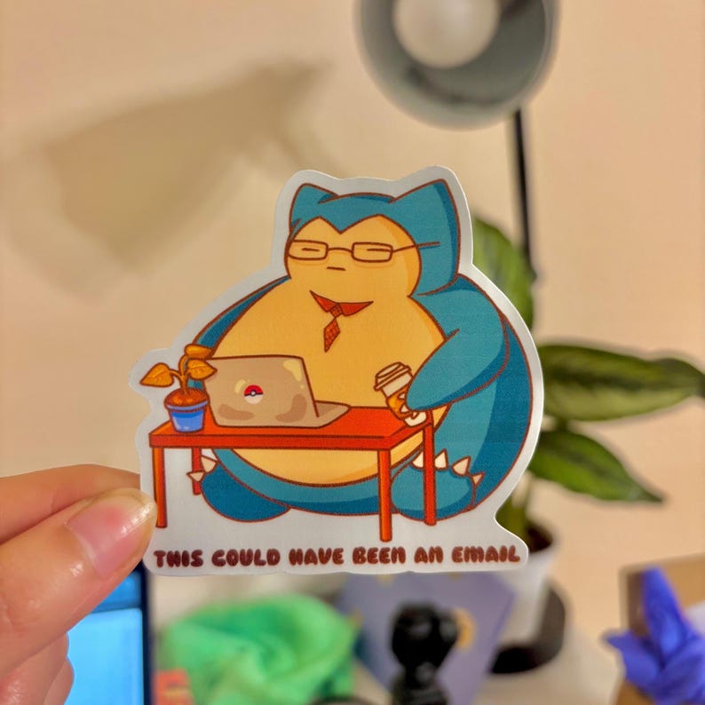 May include: A sticker featuring a cartoon Snorlax character wearing glasses and a tie, working at a desk with a laptop and coffee. The text "THIS COULD HAVE BEEN AN EMAIL" is at the bottom. The sticker is colorful with blue, yellow, and red accents.