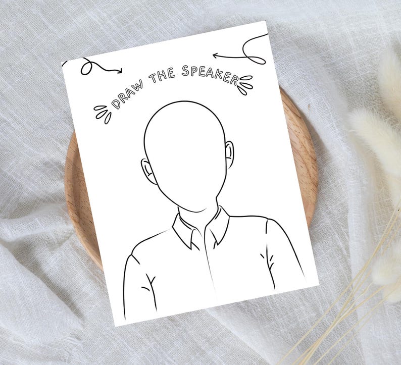 Pode incluir: Um papel branco com um desenho de contorno preto de uma pessoa sem rosto. O texto "DRAW THE SPEAKER" est&aacute; acima do desenho, com setas apontando para o desenho. O desenho est&aacute; em um prato de madeira.