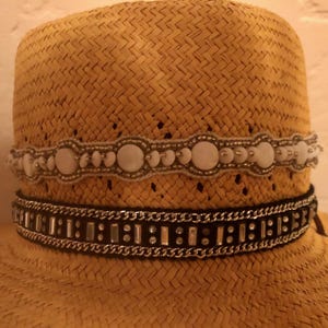 May include: A yellow straw hat with a black and silver beaded band and a white beaded band with white shell accents.