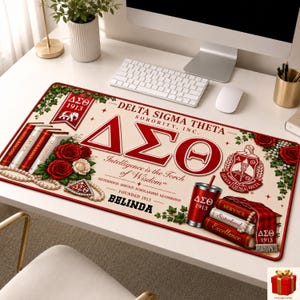 May include: A rectangular desk mat featuring Delta Sigma Theta Sorority, Inc. branding in crimson and cream. The design includes the Greek letters &Delta;&Sigma;&Theta;, the sorority crest, red roses, stacks of books labeled with core values, and the name BELINDA.