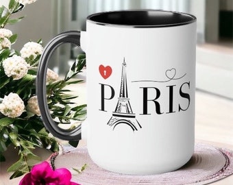 May include: White ceramic mug with a black rim and handle. The mug features a black and white illustration of the Eiffel Tower with the word "PARIS" in black text. A red heart with a keyhole is above the tower.