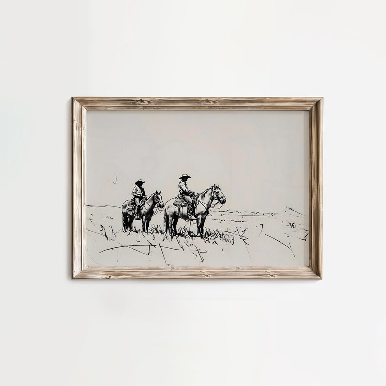 May include: A black and white line drawing of two cowboys riding horses in a field. The drawing is framed in a light wood frame.
