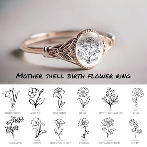 May include: A gold ring with a mother-of-pearl inlay featuring a delicate floral design. The ring is a birth flower ring, with each month's flower depicted below the ring. The flowers include snowdrop, violet, daffodil, daisy, lily of the valley, rose, larkspur, poppy, morning glory, cosmos, chrysanthemum, and holly.