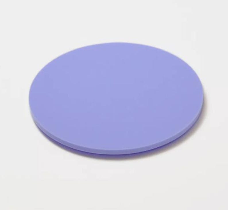 May include: A solid, round coaster in a soft periwinkle color. The coaster is made of a smooth material and is designed to protect surfaces from drink condensation. The simple design makes it suitable for various home decor styles.
