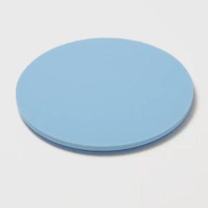 May include: A solid, light blue, round coaster. The coaster is made of a smooth material and is designed to protect surfaces from drink condensation. The coaster is a simple, minimalist design.