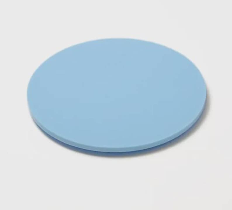 May include: A solid, light blue, round coaster. The coaster is made of a smooth material and is designed to protect surfaces from drink condensation. The coaster is a simple, minimalist design.