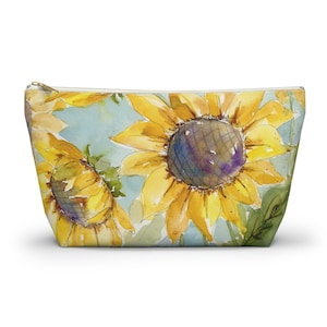 May include: A watercolor painting of sunflowers on a light blue background. The sunflowers are yellow with brown centers and green leaves. The painting is on a white canvas.