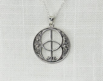 May include: A silver pendant necklace with a circular pendant. The pendant has a detailed Celtic knot design, with a vertical and horizontal line intersecting in the centre. The necklace hangs on a delicate silver chain.