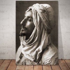 Può includere: Una fotografia vintage in bianco e nero di un uomo con un tradizionale copricapo bianco. L'uomo guarda in alto e a destra. La foto è etichettata "Bedouin".