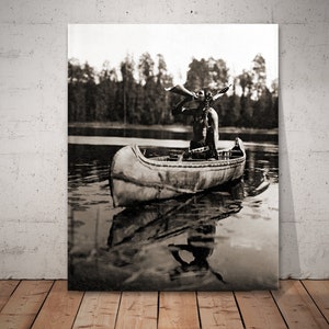 The Moose Call - Ojibway man in canoe, blowing a moose call. Photographed by Roland W. Reed in Minnesota.