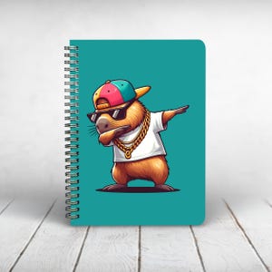 May include: A teal blue notebook with a spiral binding features a cartoon capybara wearing sunglasses, a gold chain, and a backwards baseball cap. The capybara is doing the "dab" dance pose.