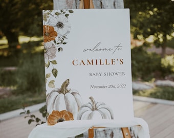 Op de afbeelding: Een wit bord met een herfstthema verwelkomt gasten op de babyshower van Camille op 20 november 2022. Het bord bevat aquarel illustraties van pompoenen en bloemen.