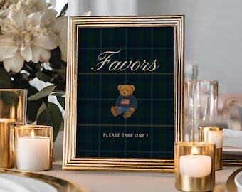 Könnte beinhalten: Ein goldgerahmtes Schild mit dem Wort "Favors" in Schreibschrift, einer Teddybär-Grafik und dem Text "PLEASE TAKE ONE!". Das Schild steht auf einem Tisch mit goldenen Akzenten, Kerzen und weißen Blumen.