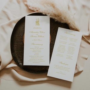 Könnte beinhalten: Hochzeitsprogramme und eine Dankeskarte mit goldfarbenen Buchstaben auf weißem Hintergrund. Die Programme listen die Namen des Paares, das Datum und die Zeremoniedetails auf. Die Karten liegen auf einem dunkelbraunen, strukturierten Tablett.