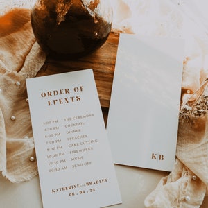Può includere: Un biglietto bianco con testo marrone che elenca l'ordine degli eventi di un matrimonio. Il testo include l'ora e l'evento, come "3:00 PM THE CEREMONY" e "10:30 PM MUSIC". Il biglietto include anche i nomi "KATHERINE e BRADLEY" e la data "06.06.23".
