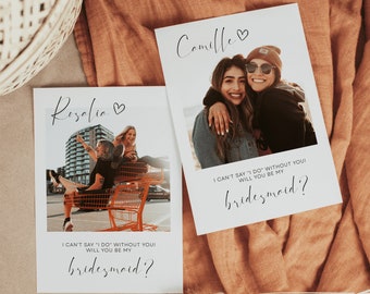 May include: Two cards with a white background and black text. The text on the cards reads "I can't say 'I do' without you! Will you be my bridesmaid?" Each card features a photo of two women smiling and hugging. The name "Camille" is written on one card and "Rezalia" is written on the other card.