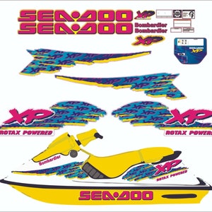 Peut inclure: Un jet ski Sea-Doo Sea-Doo 200 XP blanc avec des accents jaunes et un design graphique rose et bleu. Le design graphique comprend le texte "Sea-Doo 200", "Bombardier", "XP" et "Rotax Powered".