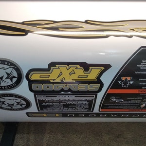 May include: Close-up view of Sea-Doo 700 decals and labels.  Features include a gray and yellow flame design, two Ultra-Low Emission circular logos, a rectangular Sea-Doo 700 label with yellow lettering, and a triangular warning label with safety information.  All decals are on a white background. The labels include text such as 'Ultra-Low Emission', 'Sea-Doo 700', and 'Warning'. The overall theme is watercraft or personal watercraft graphics and labels.