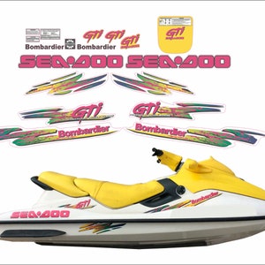 Peut inclure: Un jet ski Sea-Doo GTI blanc et jaune avec des graphismes roses et verts. Le jet ski a un siège jaune et un guidon noir. Les graphismes comprennent les mots "Sea-Doo", "GTI" et "Bombardier".