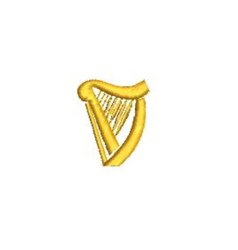 May include: A gold-colored harp embroidery design. The harp features a curved frame and a series of vertical strings. The design is set against a white background, highlighting the details of the instrument.