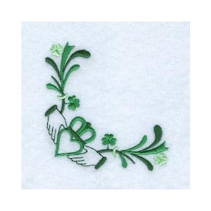 Op de afbeelding: Geborduurd ontwerp met twee handen die een groen hart vasthouden, omringd door groene klavers en bloemelementen. Het ontwerp in groen- en wittinten is perfect voor St. Patrick's Day of Ierse thema's.