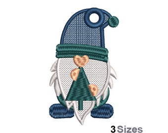 May include: Embroidered Christmas gnome ornament with a blue hat, white beard, and a green Christmas tree. The gnome is wearing a heart-shaped nose.