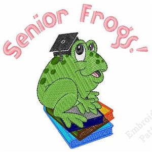May include: An embroidery design featuring a green frog with dark green spots wearing a black graduation cap. The frog sits on a stack of blue, brown, and orange books. Above the frog, the text Senior Frogs! is stitched in pink letters.