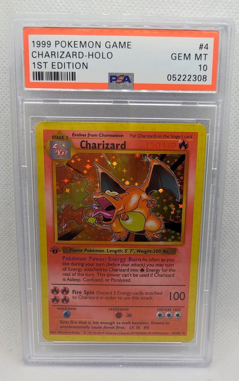 K&ouml;nnte beinhalten: Eine bewertete 1999 Pok&eacute;mon Charizard-Holo 1st Edition Karte. Die Karte zeigt eine lebendige Illustration von Charizard, einer orange-gelben drachenartigen Kreatur. Die Karte ist in einem Schutzhalter mit einer PSA-Note von 10 eingeschlossen.