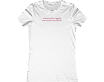 Pode incluir: Camiseta branca com o texto "the feminine urge to destroy the patriarchy" em rosa.