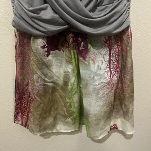 Pode incluir: Um vestido cinza e branco com estampa floral. A parte superior do vestido &eacute; de tecido cinza liso e a parte inferior &eacute; de tecido branco com uma estampa floral em tons de rosa, verde e marrom.