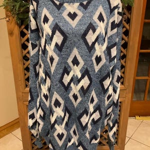 May include: A long-sleeve knit sweater featuring a repeating geometric diamond pattern in shades of navy blue, light blue, and white. The garment has a crew neckline with a ribbed collar, ribbed cuffs, and a ribbed hem, constructed from a textured yarn.