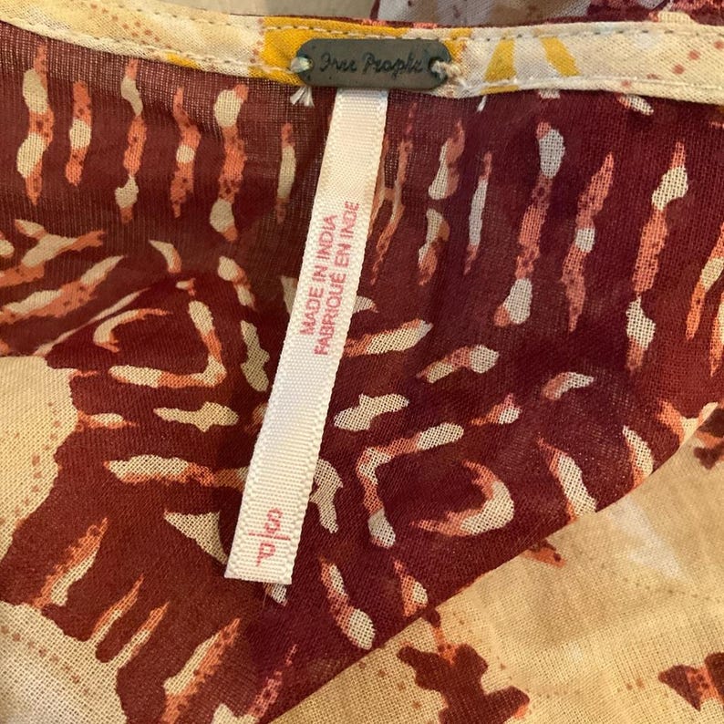 May include: Close-up of a patterned fabric with a tag. The fabric features a burgundy and cream design. The tag reads "Free People" and "Made in India / Fabriqu&eacute; en Inde". The tag also has the size "S/P".