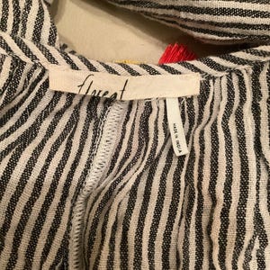 May include: Close-up of a black and white striped garment with the word "florest" printed on a tag. The tag also reads "MADE IN INDIA". The garment has a textured appearance and a decorative trim.