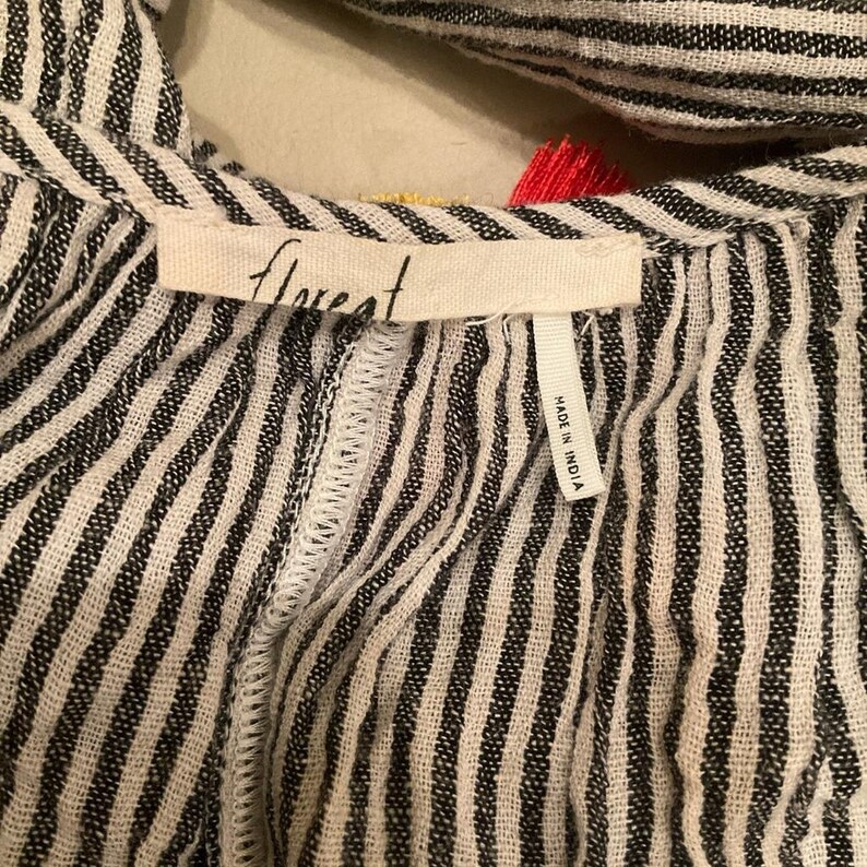 May include: Close-up of a black and white striped garment with the word "florest" printed on a tag. The tag also reads "MADE IN INDIA". The garment has a textured appearance and a decorative trim.