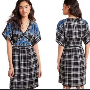 May include: A black and white plaid dress with blue floral embroidery on the sleeves and bodice. The dress has a V-neckline and a fitted waist. The sleeves are short and the skirt falls to the knees.