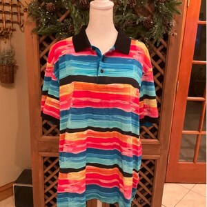 May include: A colorful polo shirt with horizontal stripes in shades of red, blue, orange, and yellow. The shirt has a black collar and short sleeves. The shirt is displayed on a white mannequin.