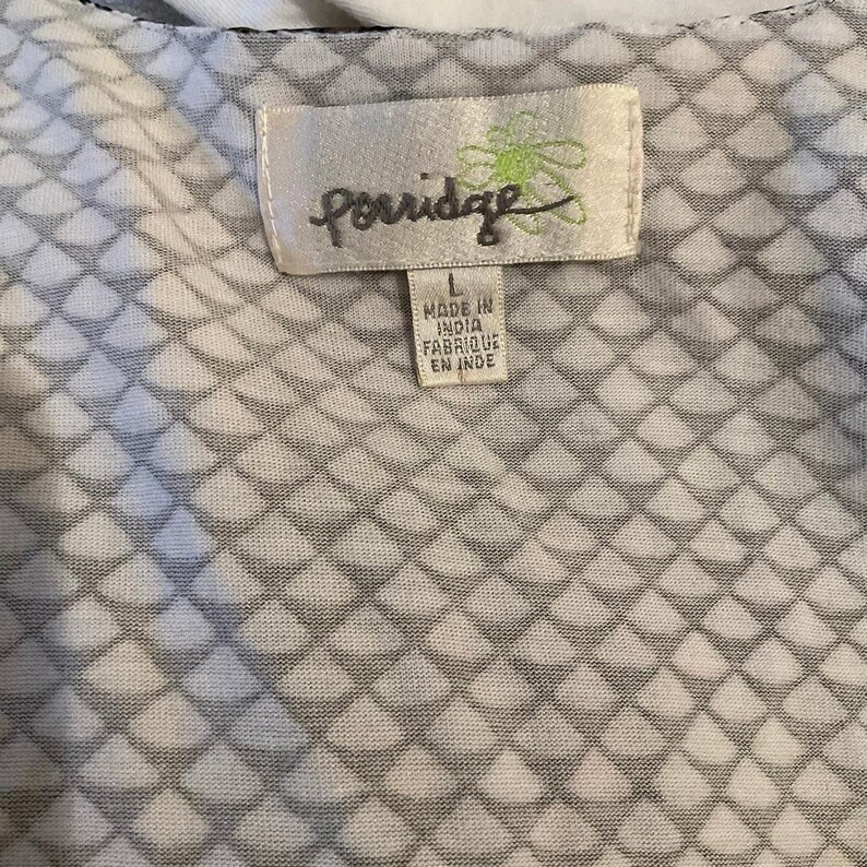 Puede incluir: Primer plano de una tela estampada en blanco y gris. La tela tiene un dise&ntilde;o de diamantes repetidos. Una etiqueta dice "Porridge" con el texto "Made in India Fabriqu&eacute; en Inde".