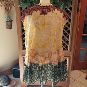 May include: A sleeveless dress with a floral pattern in shades of yellow, orange, and cream. The top section is a deep burgundy with a geometric design. The bottom has a green and black geometric pattern.