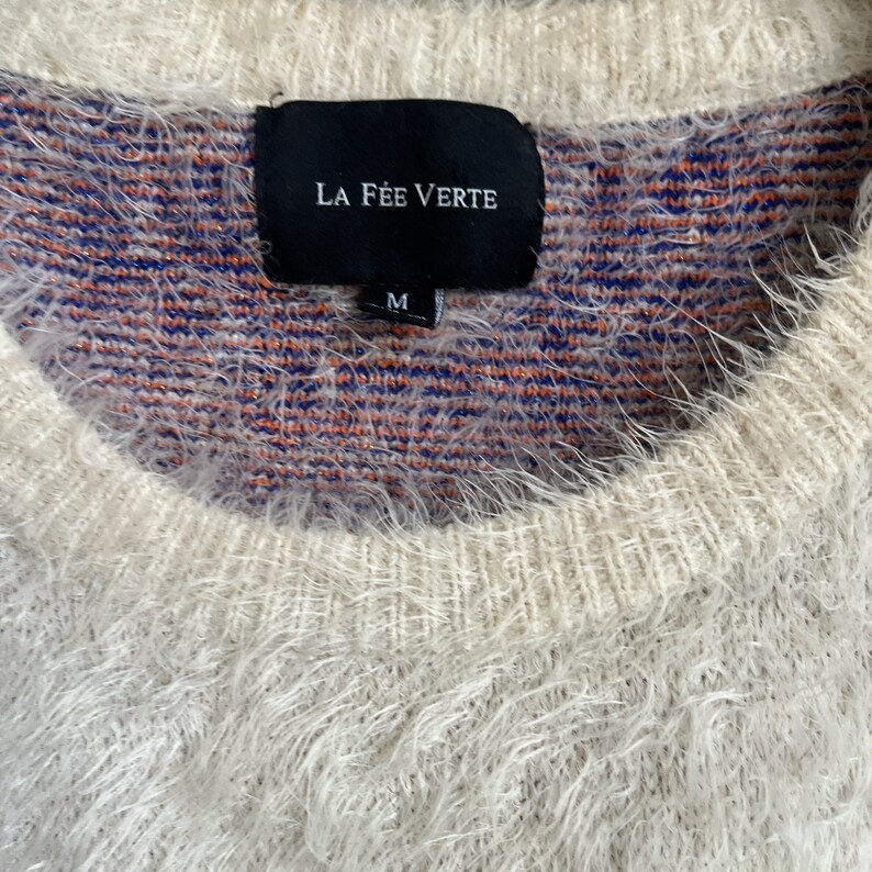 May include: A white fuzzy sweater with a black tag that says "LA F&Eacute;E VERTE" and "M" in white lettering.