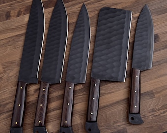 May include: Five black kitchen knives with wooden handles. The knives are arranged in a row on a wooden surface. The knives have different blade shapes and sizes.