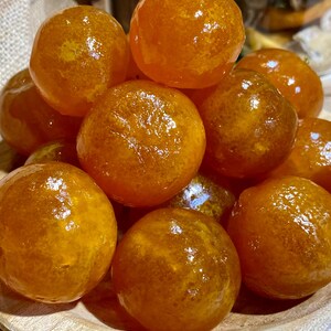 Peut inclure: Un bol de fruits d'agrumes confits orange. Les fruits sont ronds et brillants, d'une couleur orange vif.