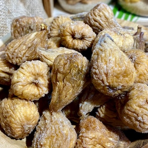 Peut inclure: Un bol de figues séchées, enrobées d'un glaçage blanc sucré. Les figues sont de couleur brun clair et ont une texture ridée.