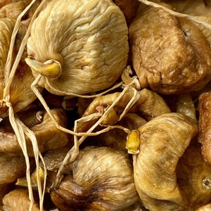Peut inclure: Gros plan sur un bouquet de figues séchées liées ensemble avec de la ficelle. Les figues sont de couleur brun foncé et ont une texture ridée.