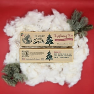 May include: Two boxes of "Christmas Tree" incense sticks are displayed on a bed of white fluff and a red background. The boxes are brown with green and gold Christmas tree illustrations and the text "The World Makes Scents". The boxes also include the text "Handcrafted in Bridgeport".