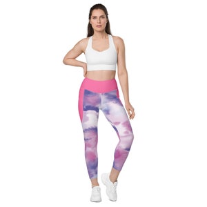 May include: A woman wearing a white sports bra and pink and purple tie-dye leggings with a pink waistband. The leggings have a side pocket on the left leg.