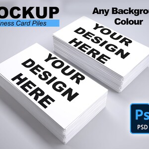 Puede incluir: Dos pilas de tarjetas de visita blancas con el texto "YOUR DESIGN HERE" en negrita negra. La palabra "MOCKUP" está en la parte superior, con "Business Card Piles" debajo. El texto "Any Background Colour" también es visible, junto con un icono de Photoshop PSD.