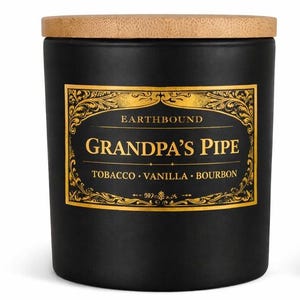 Puede incluir: Un tarro de vela negro con tapa de madera. La etiqueta dice "GRANDPA'S PIPE" con notas de tabaco, vainilla y bourbon. El tarro es cilíndrico y tiene un acabado mate. La etiqueta es dorada con texto negro.